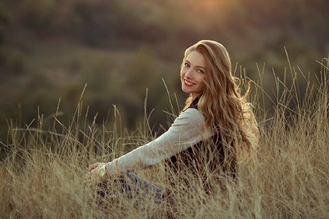 Smiling happy cheerful girl with beautiful smile sit on hills